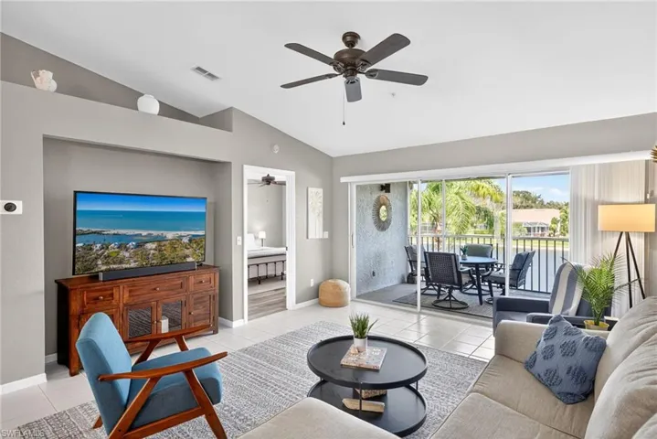 Living area with light tile patterned floors, ceiling fan, and vaulted ceiling