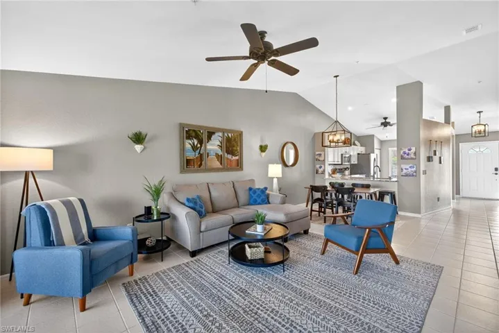 Living room featuring a ceiling fan, suspended lighting, light tile patterned floors, and a high ceiling
