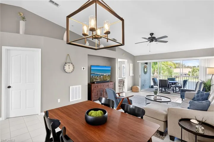 Dining room featuring lofted ceiling, light tile patterned floors, a ceiling fan, and suspended lighting