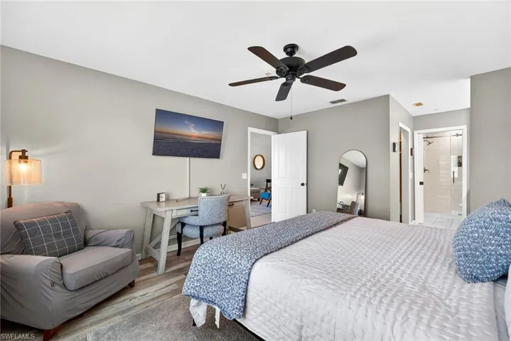 Bedroom featuring wood finished floors, a ceiling fan, and ensuite bath