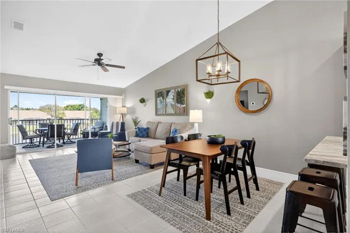 Dining space featuring a ceiling fan, lofted ceiling, hanging lights, and light tile patterned floors