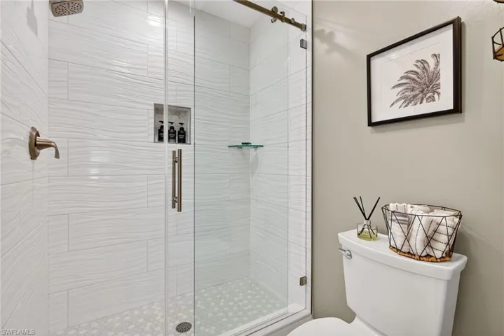 Full bath featuring a shower stall and toilet