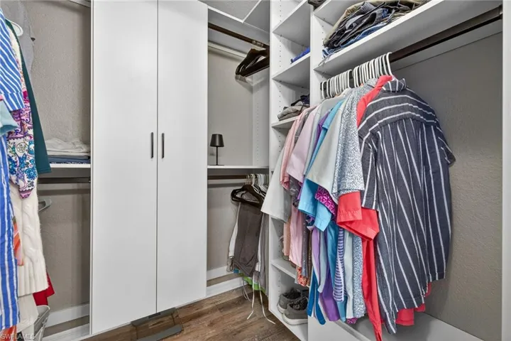 Walk in closet with dark wood-style flooring
