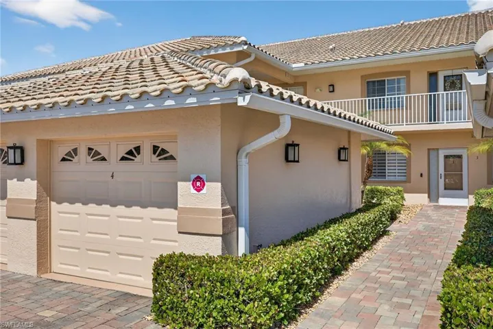 View of side of property with stucco siding, a balcony, a tiled roof, and an attached garage
