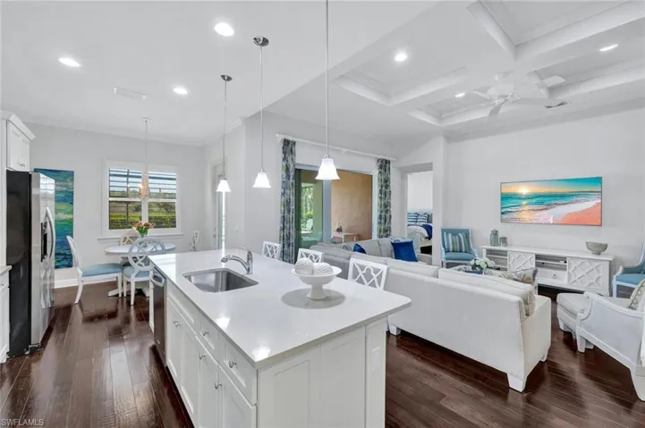 Kitchen with quartz countertops, white wood cabinetry, stainless steel appliances, hardwood floors and breakfast nook.