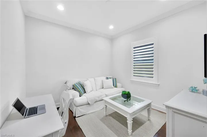 Den/office with hardwood floor and plantation shutters.