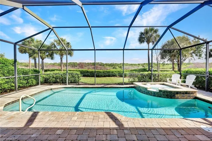 View from covered area of the pavered lanai, pool, spa and preserve view.