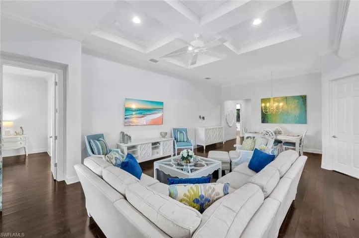 Family room with hardwood floors, custom ceiling, access to the primary bedroom (to the lef right) and dining room area/front door.