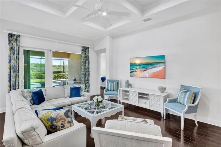 Family room with hardwood floors, custom ceiling, access to the primary bedroom (to the far right) and access to the outdoor area (lanai, pool & spa) via the sliding glass doors.