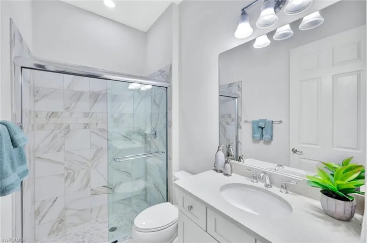 Guest bathroom with tiled shower, white wood cabintry and quartz counters.