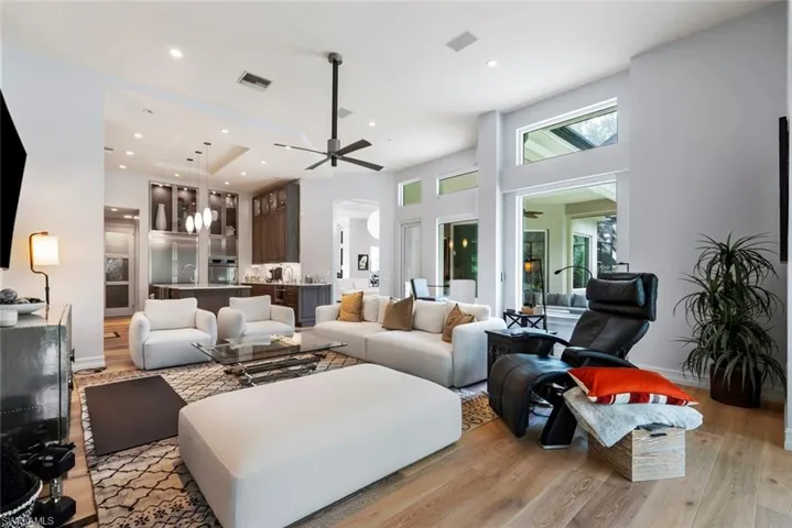 Living area featuring light wood-style flooring, ceiling fan, a high ceiling, recessed lighting, and arched walkways