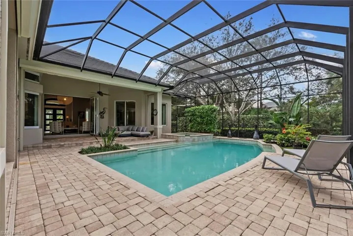 View of swimming pool featuring a patio, an outdoor living space, a ceiling fan, a pool with connected hot tub, and glass enclosure