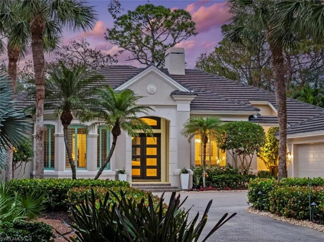 View of front of property with a chimney, a tile roof, stucco siding, and an attached garage