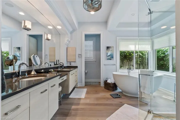 Full bath featuring vanity, baseboards, a soaking tub, wood finished floors, and a stall shower