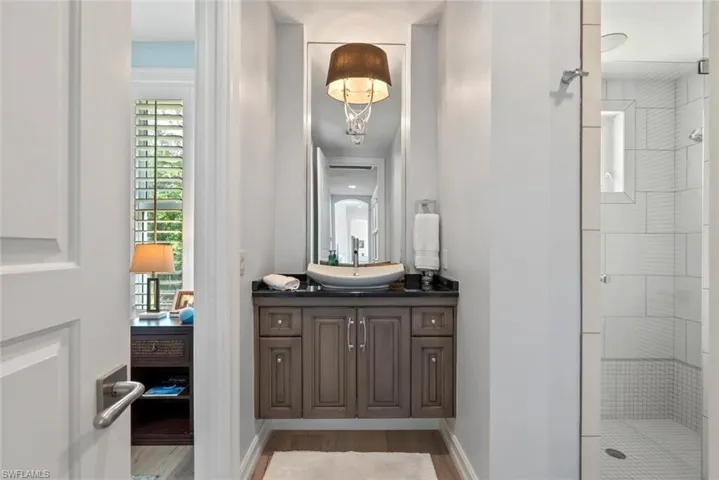 Full bath featuring vanity, a shower stall, wood finished floors, and baseboards