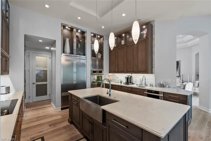 Kitchen with stainless steel appliances, arched walkways, a sink, light wood finished floors, and recessed lighting
