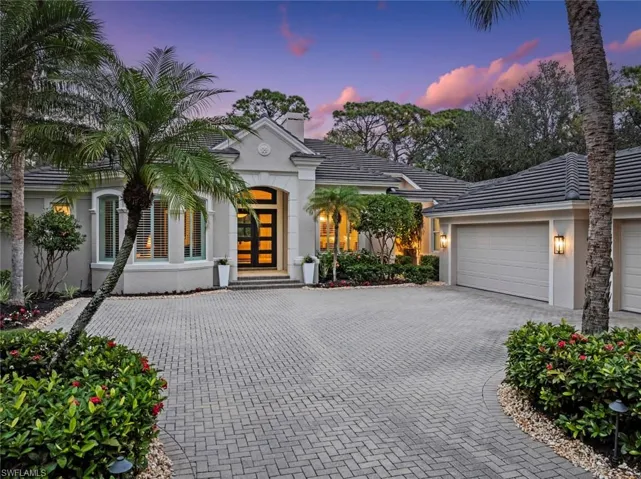 View of front of property featuring stucco siding, decorative driveway, a garage, and a tiled roof