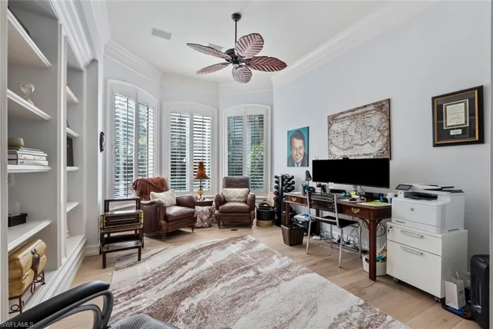 Office area featuring ceiling fan, ornamental molding, plenty of natural light, light wood-type flooring, and built in shelves