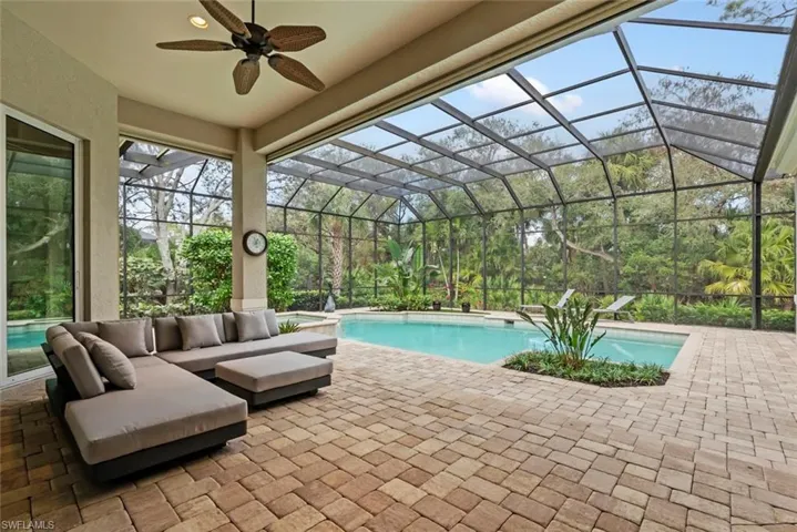 Outdoor pool featuring a patio area, ceiling fan, and glass enclosure