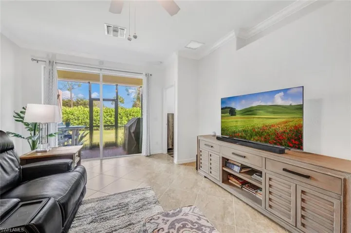 Tiled living room featuring ceiling fan and crown molding