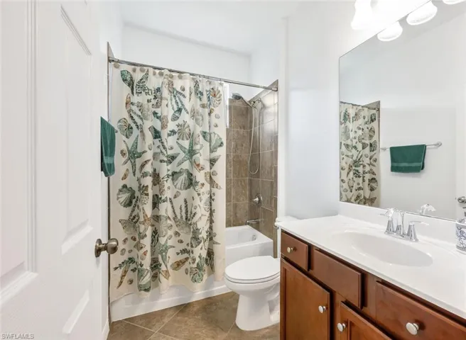 Full bathroom featuring tile patterned flooring, shower / bath combination with curtain, toilet, and vanity