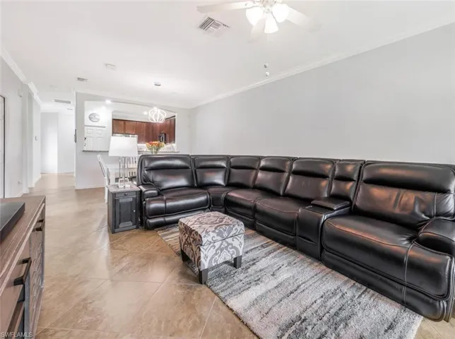 Living room featuring crown molding, ceiling fan, and light tile patterned floors
