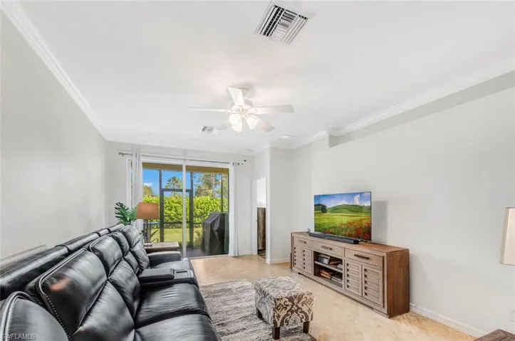 Tiled living room featuring ceiling fan and crown molding