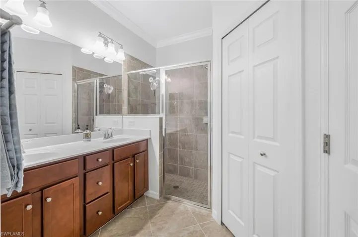Bathroom featuring tile patterned flooring, vanity, an enclosed shower, and ornamental molding