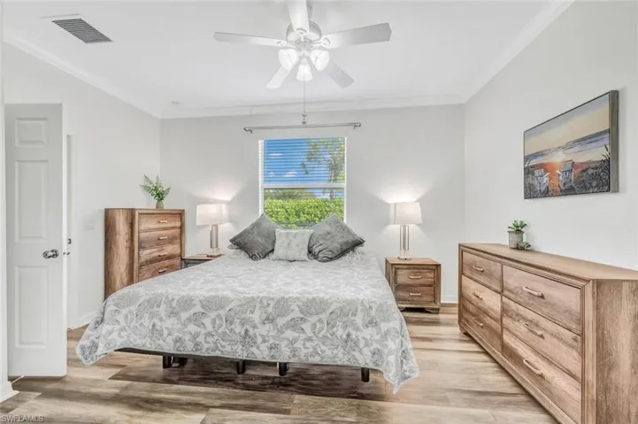 Bedroom featuring light hardwood / wood-style floors, ceiling fan, and ornamental molding