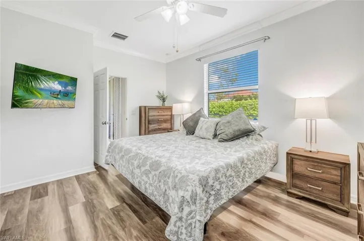 Bedroom with light wood-type flooring, ceiling fan, and ornamental molding
