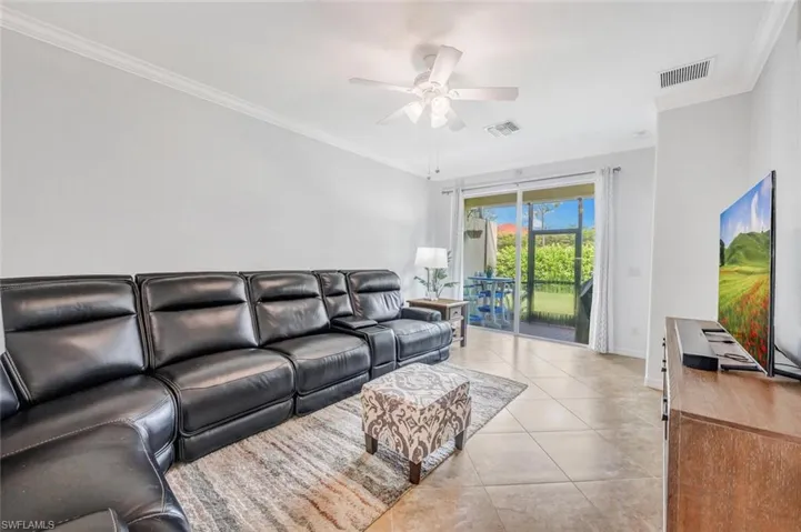 Living room with ceiling fan, ornamental molding, and light tile patterned flooring