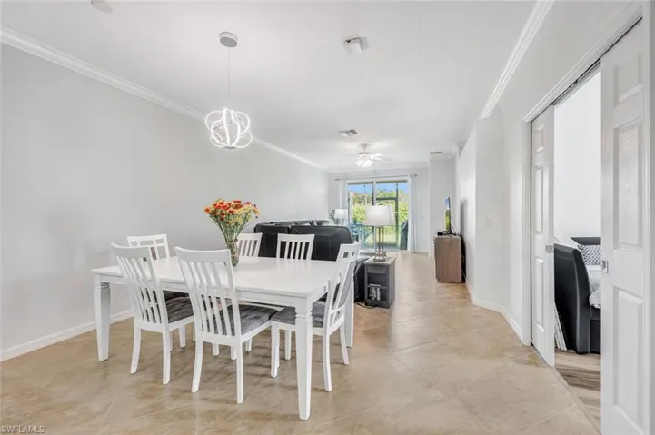 Dining room with ceiling fan, light tile patterned flooring, and ornamental molding