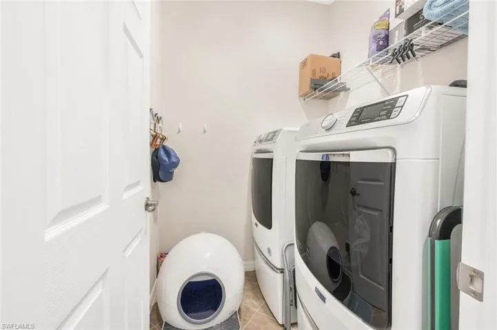 Laundry room featuring light tile patterned floors and washing machine and clothes dryer