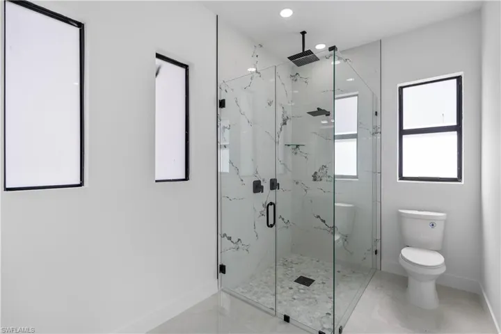 Full bathroom with a marble finish shower and recessed lighting