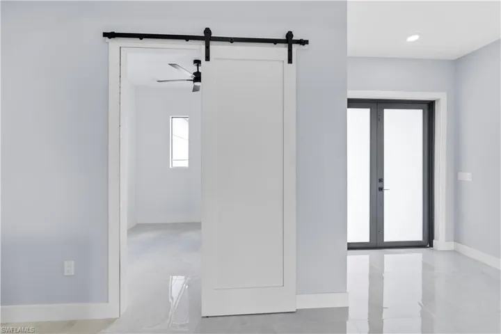 Spare room featuring a barn door, ceiling fan, and french doors