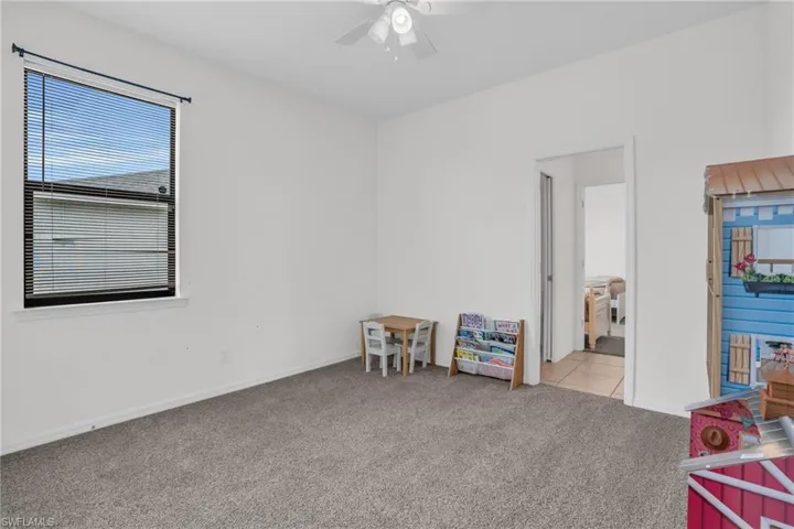 Rec room with light colored carpet, ceiling fan, and a healthy amount of sunlight