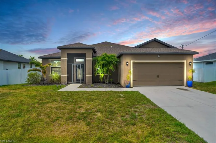 View of front facade with a garage and a lawn