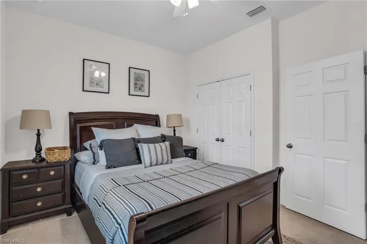 Bedroom with ceiling fan, a closet, and light carpet