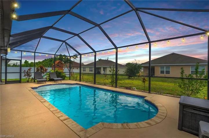 Pool at dusk featuring a yard, a lanai, and a patio
