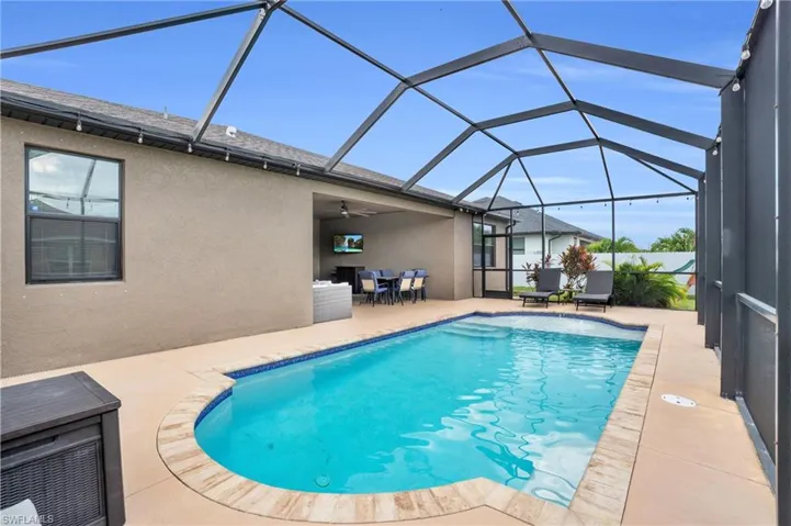 View of swimming pool with glass enclosure, a patio area, and ceiling fan