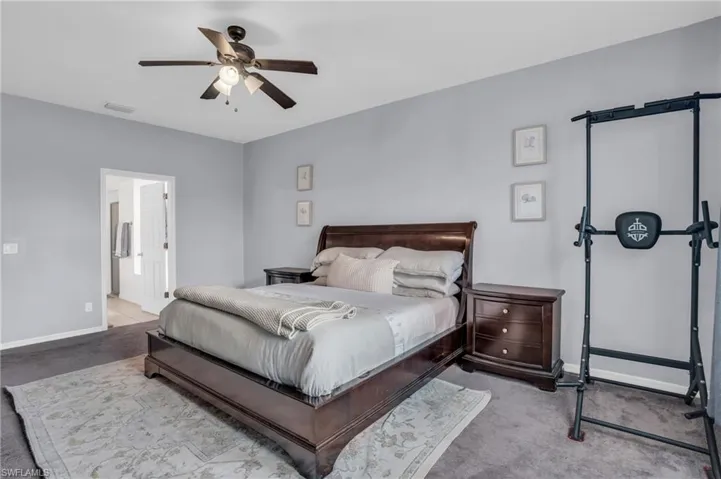Bedroom featuring ceiling fan, connected bathroom, and carpet flooring