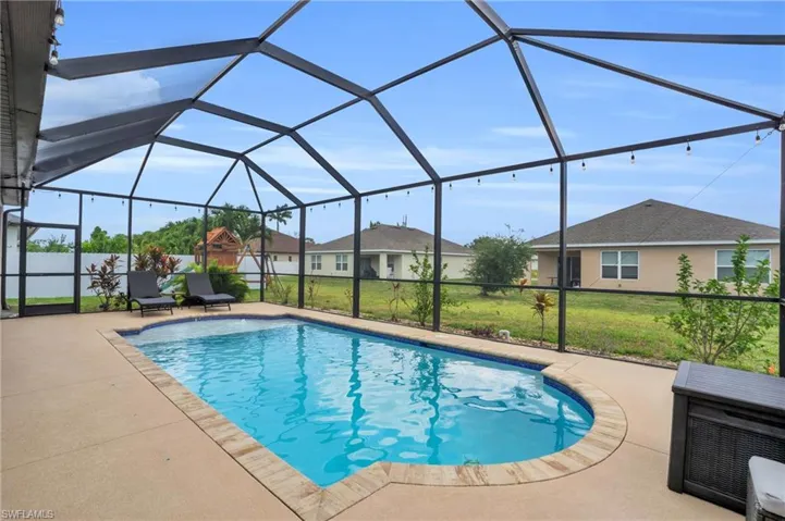 View of pool with a patio, glass enclosure, and a lawn