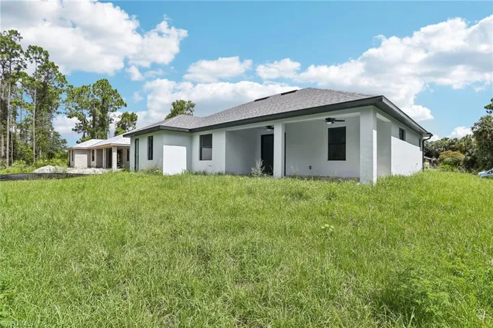Rear view of property featuring a lawn and ceiling fan