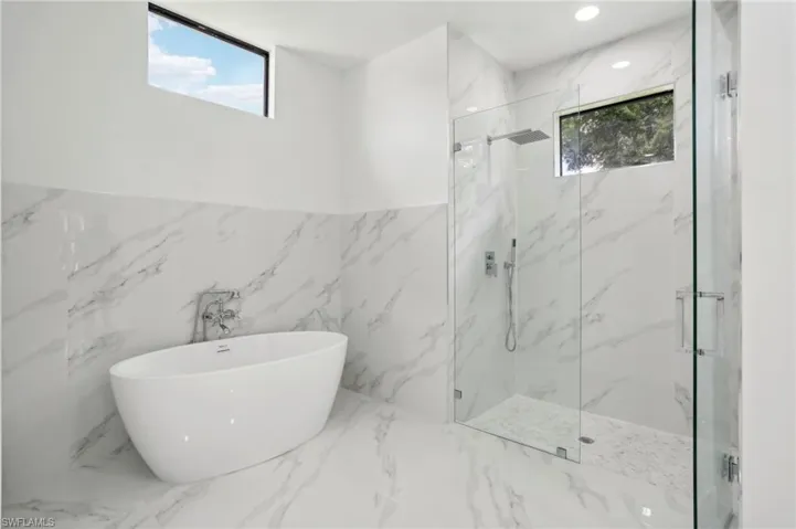 Bathroom featuring plus walk in shower, tile floors, and tile walls