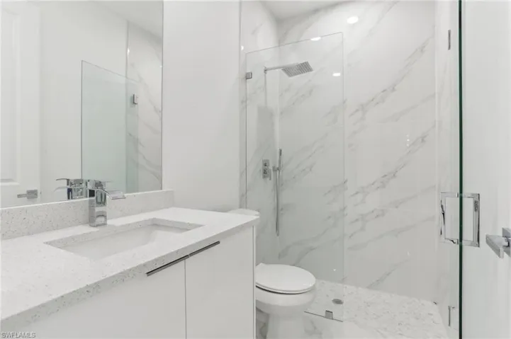 Bathroom with a shower with door, tile flooring, toilet, and vanity