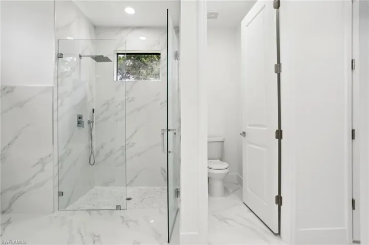 Bathroom featuring tile floors, a shower with shower door, and toilet