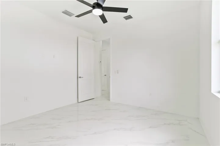 Empty room with ceiling fan and light tile flooring