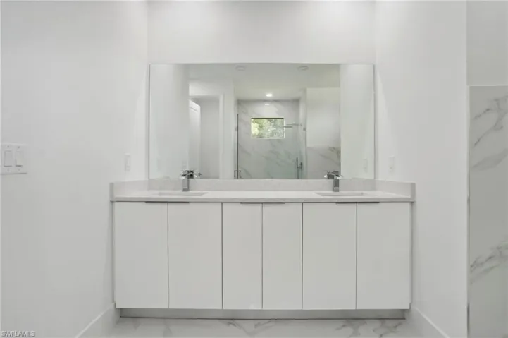 Bathroom with dual bowl vanity, tile flooring, and tiled shower