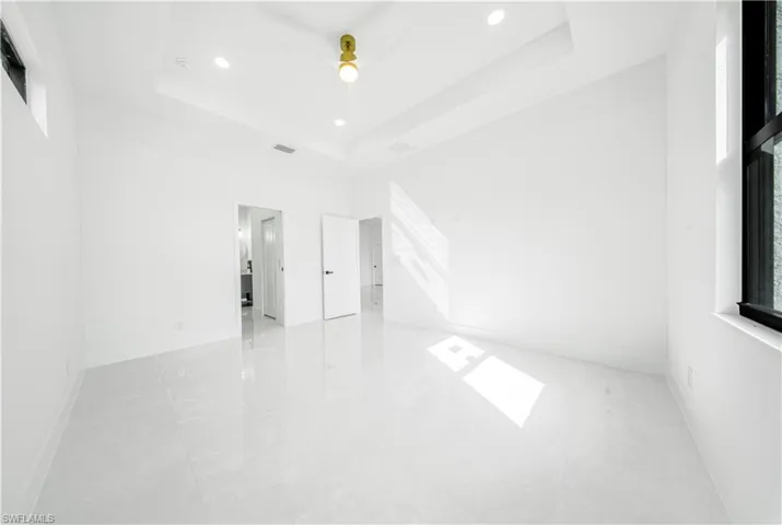 Spare room with a raised ceiling, recessed lighting, a ceiling fan, and light tile patterned floors