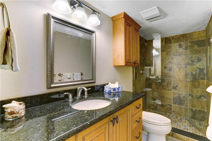 Guest bathroom with custom tiled shower, glass shower doors, granite vanity, newer lighting/plumbing fixtures.